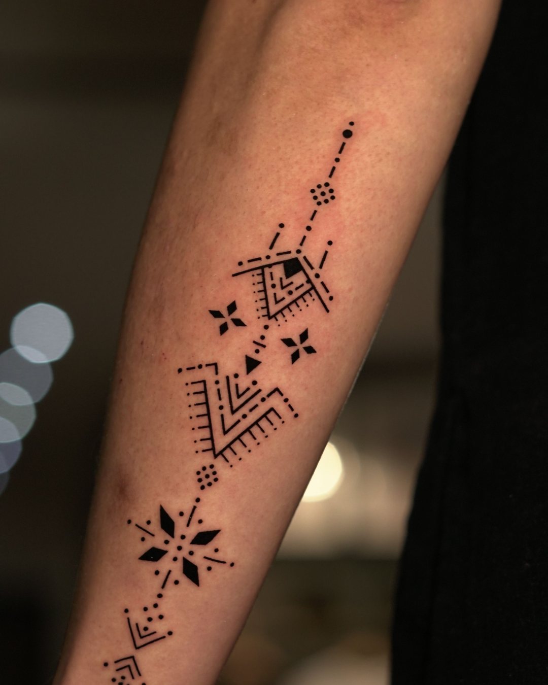 Diseño ornamental de puntos y formas geométricas en blackwork en el antebrazo