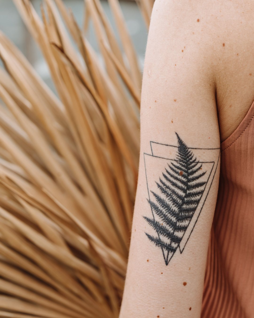 Helecho en fine line con dos triángulos en el brazo